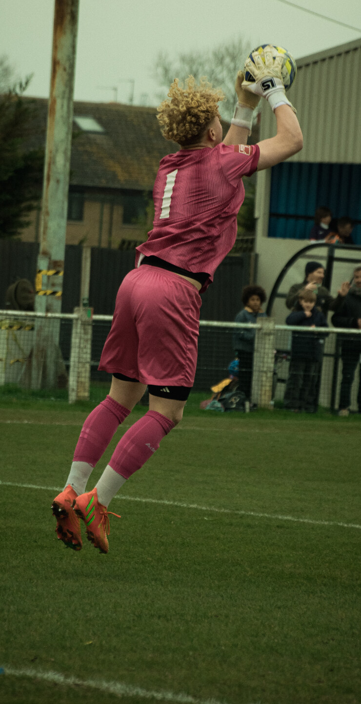 Goalkeeper in pink leaping to catch the ball