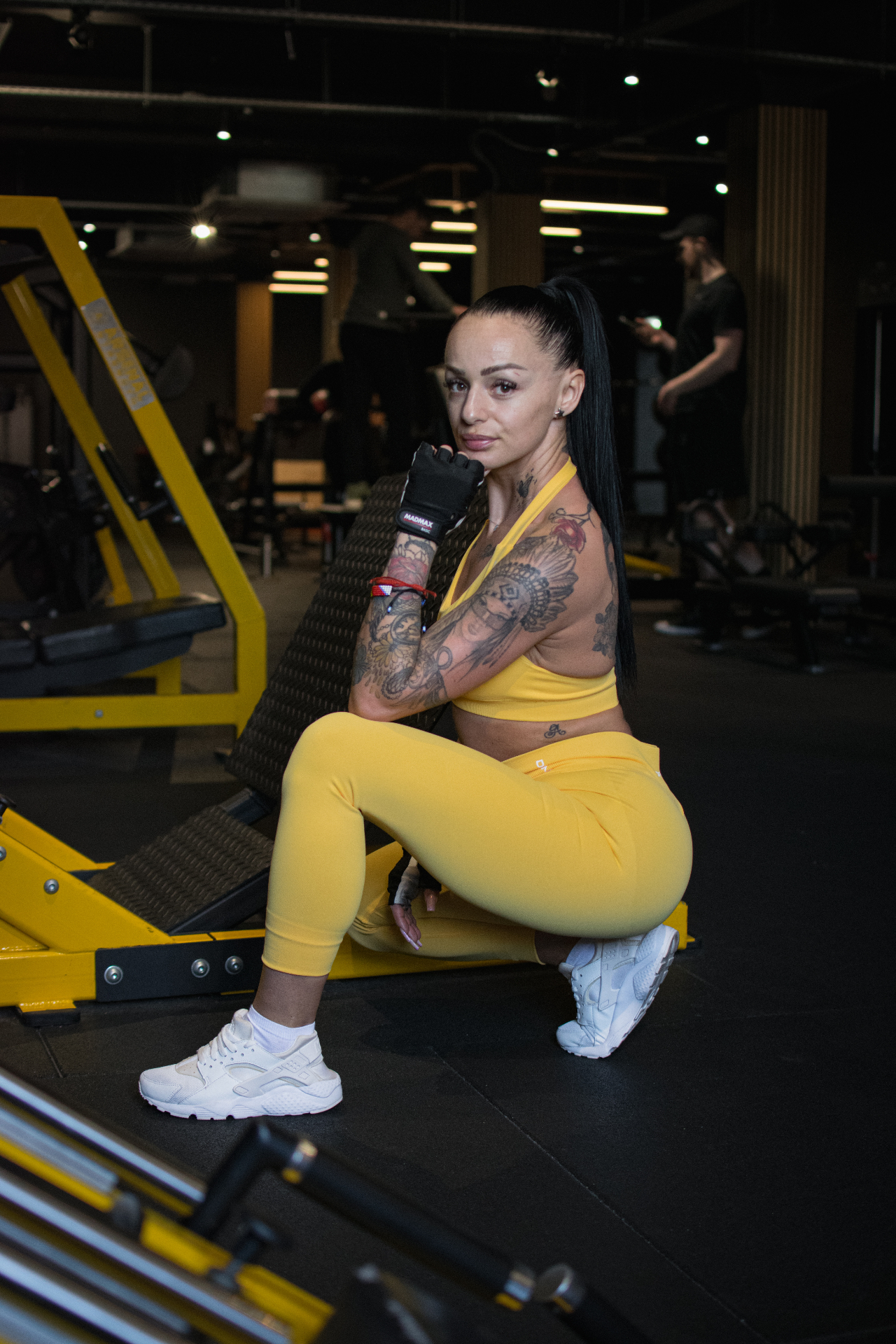 Athlete in yellow gymwear resting by a leg press machine