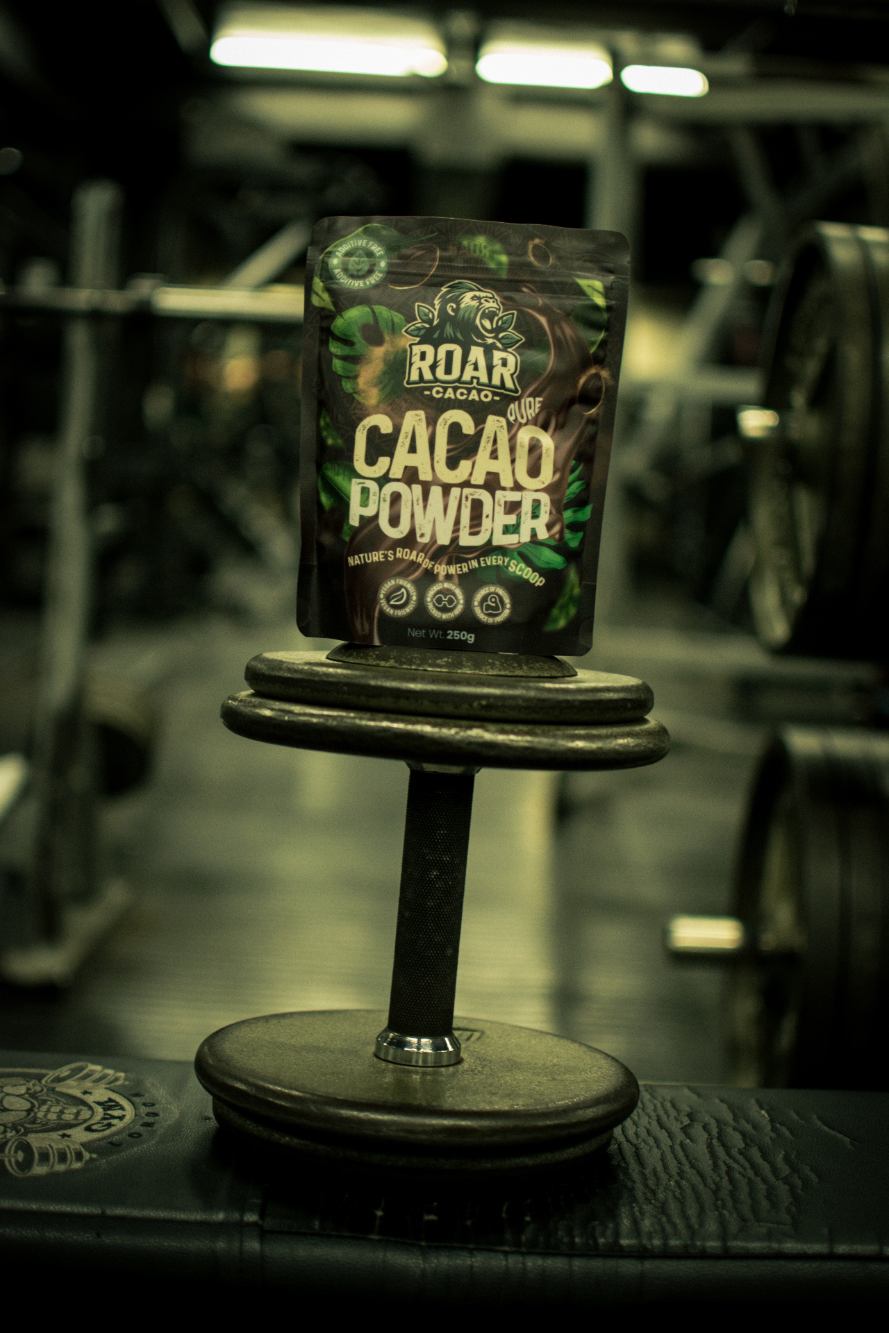 Roar Cacao pouch balanced on a dumbbell in a gym