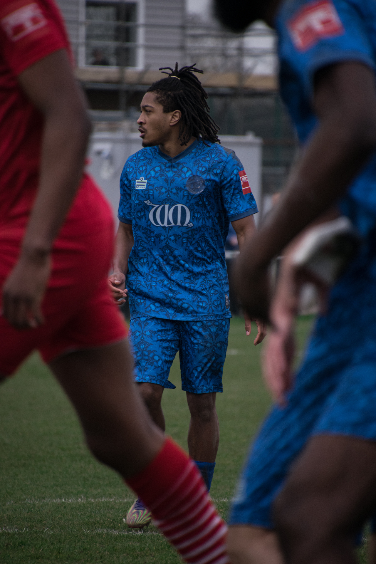 Footballer in blue patterned kit between opponents