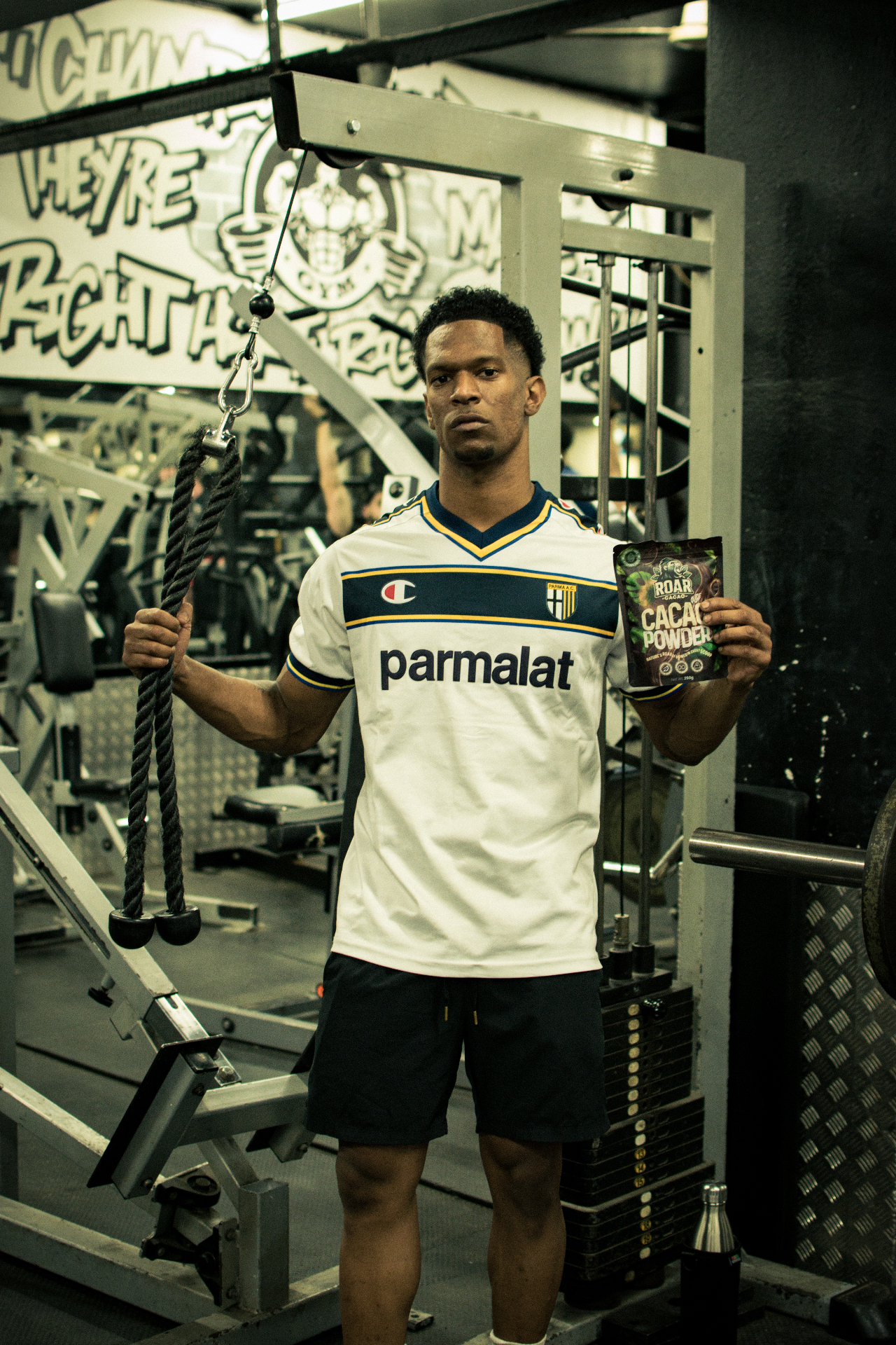Athlete in a Parma football shirt holding Roar Cacao at a cable machine