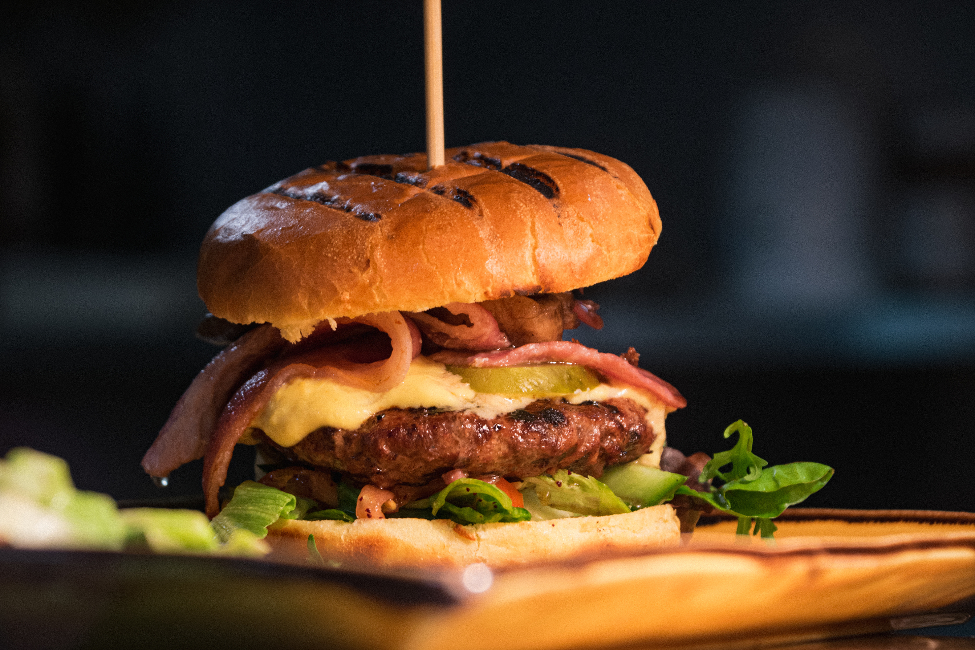 Grilled beef burger with bacon and cheese on a wooden board